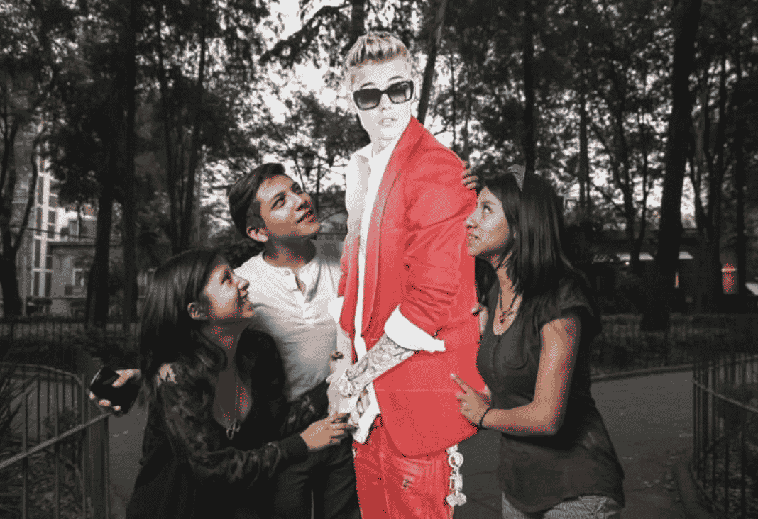 Dos mujeres y un hombre junto a una figura de cartón de Justin Bieber