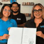 Dos mujeres y un hombre mostrando un menú escrito en braille