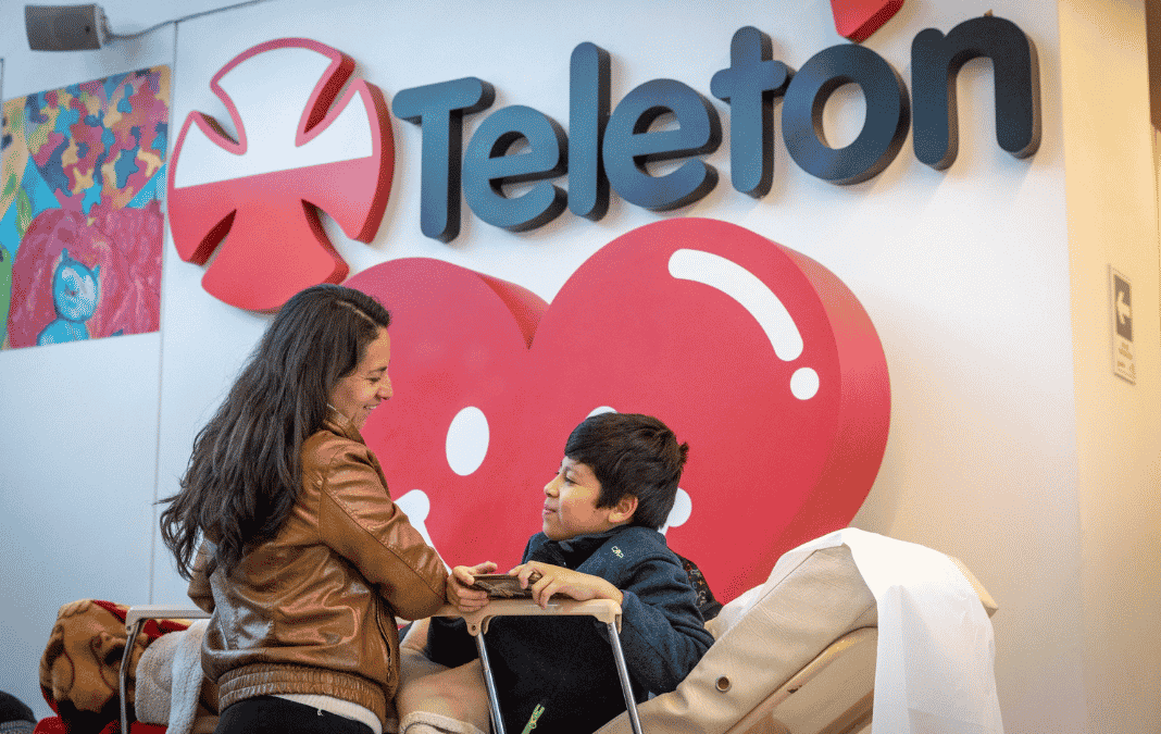 Madre e hijo con discapacidad y atrás logo de la Teletón