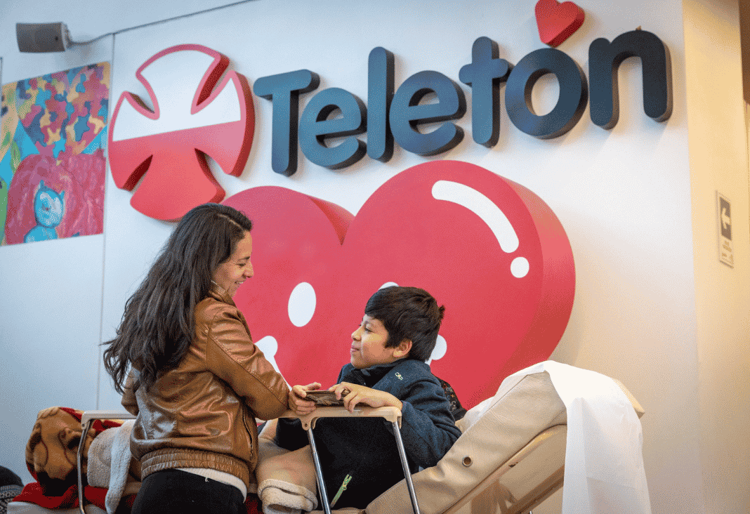Madre e hijo con discapacidad y atrás logo de la Teletón