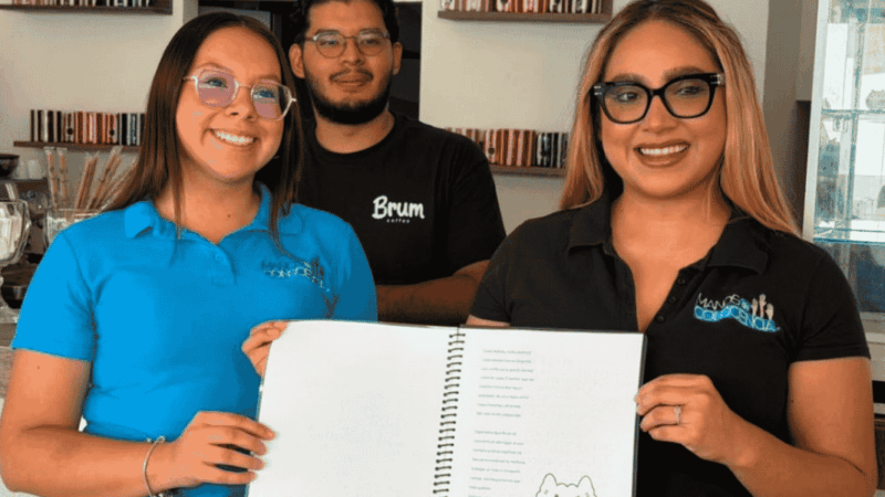 Dos mujeres y un hombre mostrando un menú escrito en braille