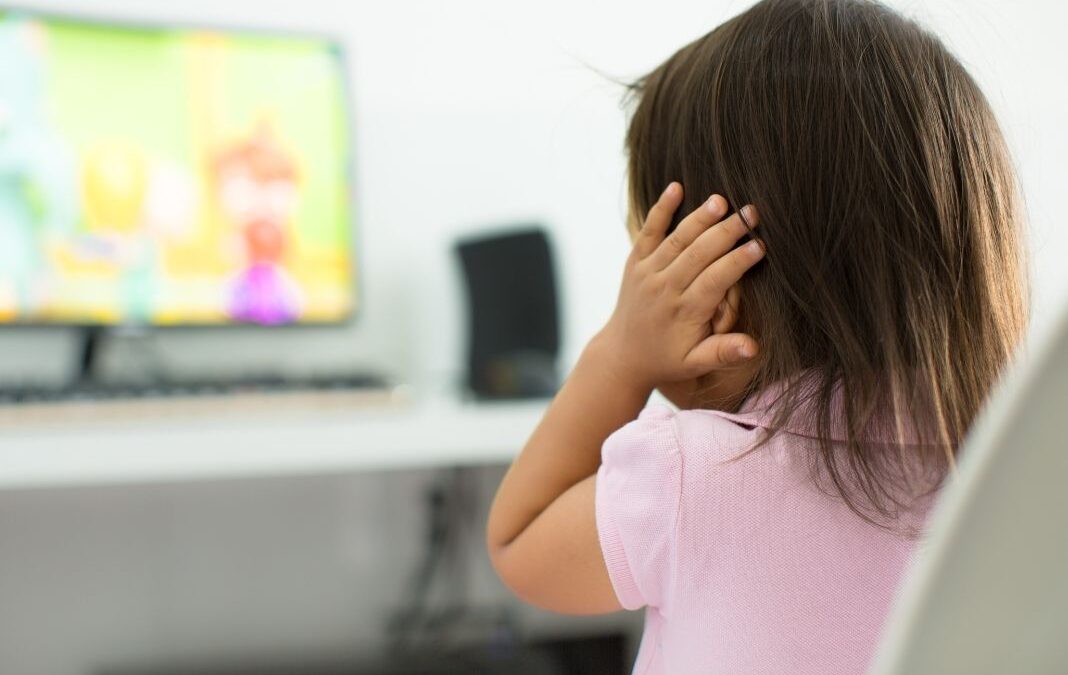 Niña de espalda tapándose los oídos
