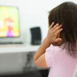 Niña de espalda tapándose los oídos