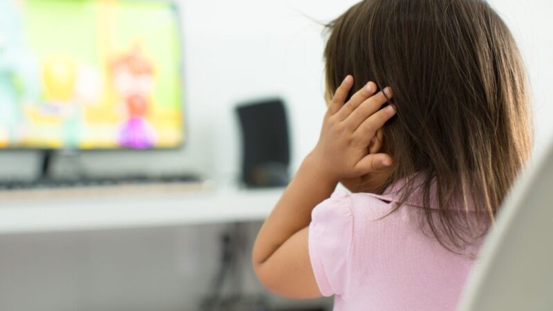 Niña de espalda tapándose los oídos