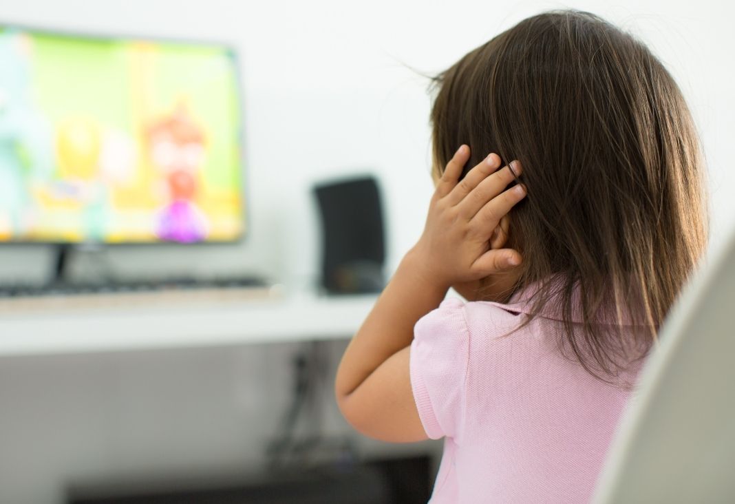 Niña de espalda tapándose los oídos