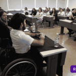 Hombre en silla de ruedas exponiendo en una sala universitaria