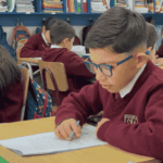 Niña y niño leyendo en una sala de clases