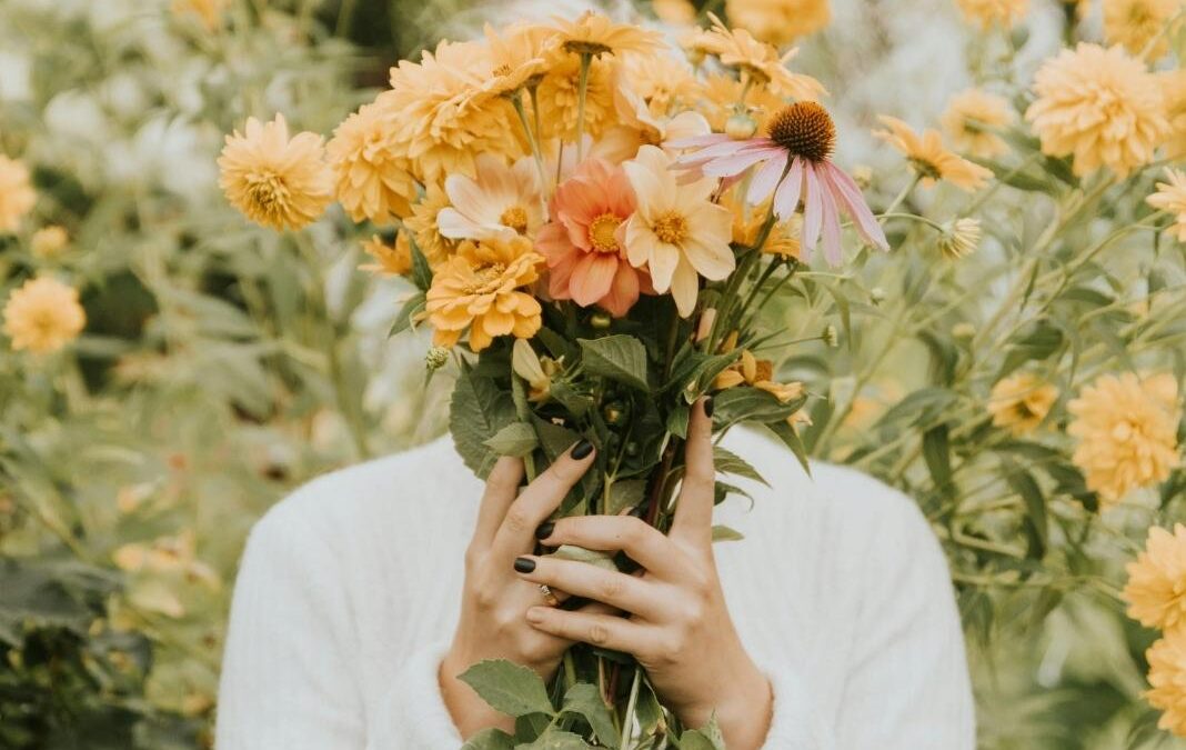 persona tapándose la cara con ramo de flores