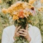 persona tapándose la cara con ramo de flores