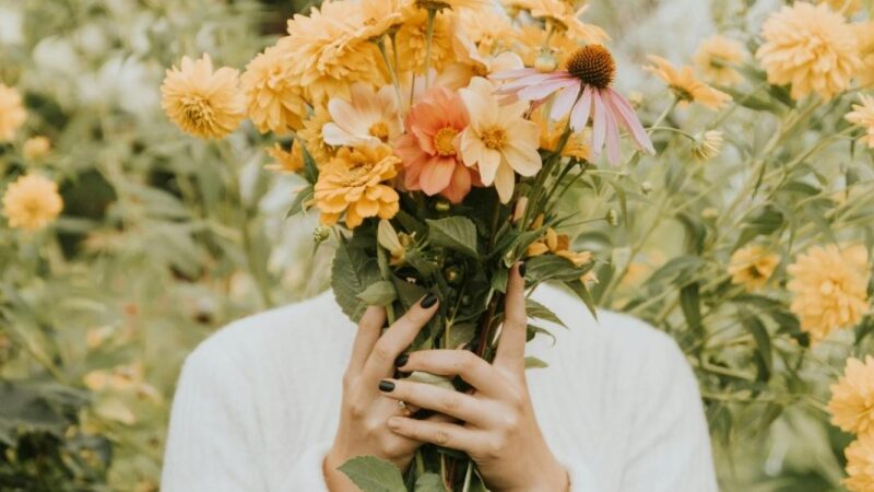 persona tapándose la cara con ramo de flores