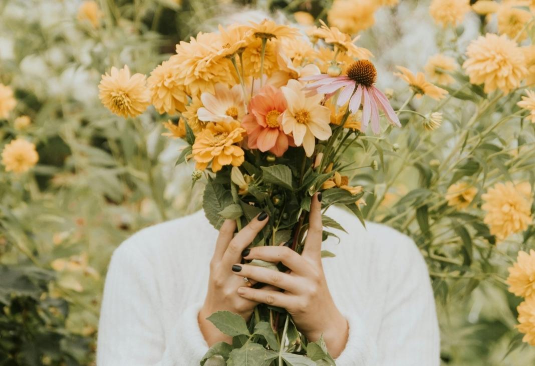 persona tapándose la cara con ramo de flores
