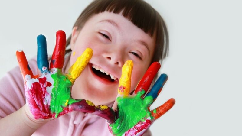 niña con síndrome de down mostrando manos pintadas