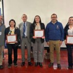 Tres mujeres con diplomas y tres hombres, todos mirando a la cámara