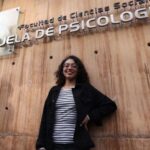 Joven mirando y sonriendo a la cámara, y arriba de ella letrero que dice "Escuela de Psicología"