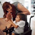 mujer junto a niño con discapacidad física dándose la mano