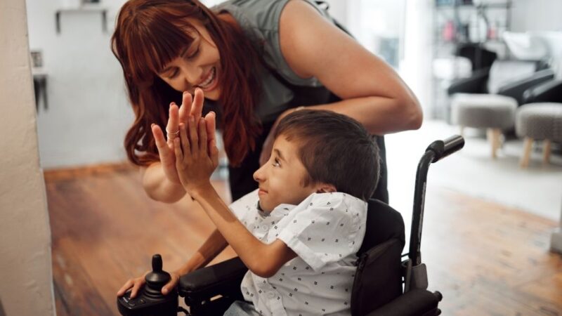 mujer junto a niño con discapacidad física dándose la mano