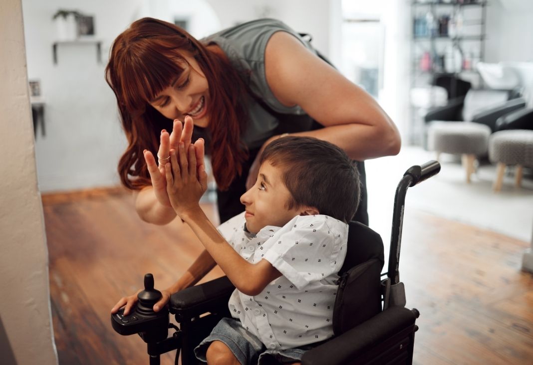 mujer junto a niño con discapacidad física dándose la mano