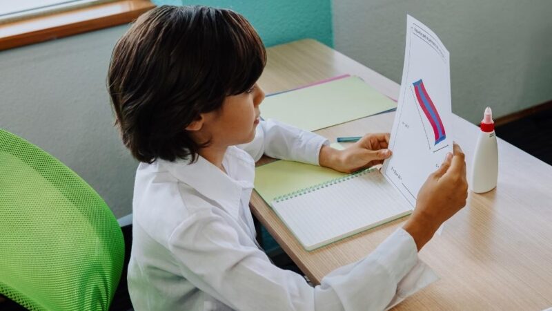 niño leyendo una hoja en una sala de clases