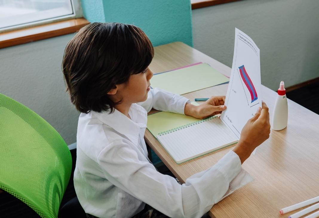 niño leyendo una hoja en una sala de clases