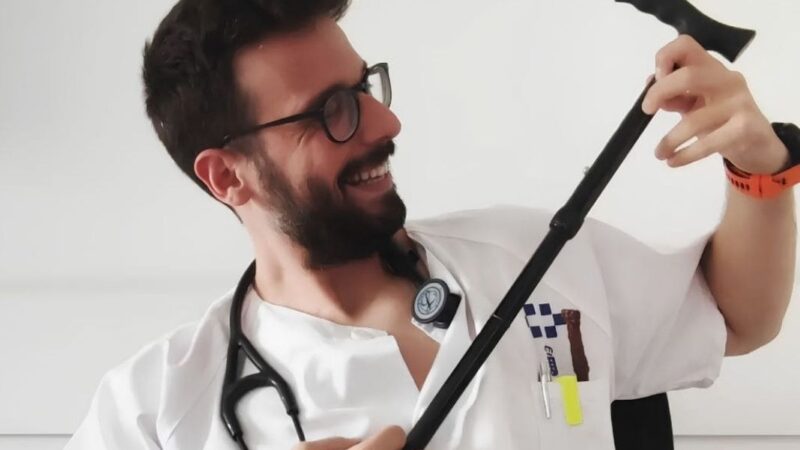 Médico sonriendo y usando un bastón como guitarra
