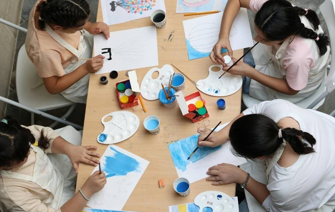 Cuatro mujeres sentadas alrededor de una mesa con materiales para pintar