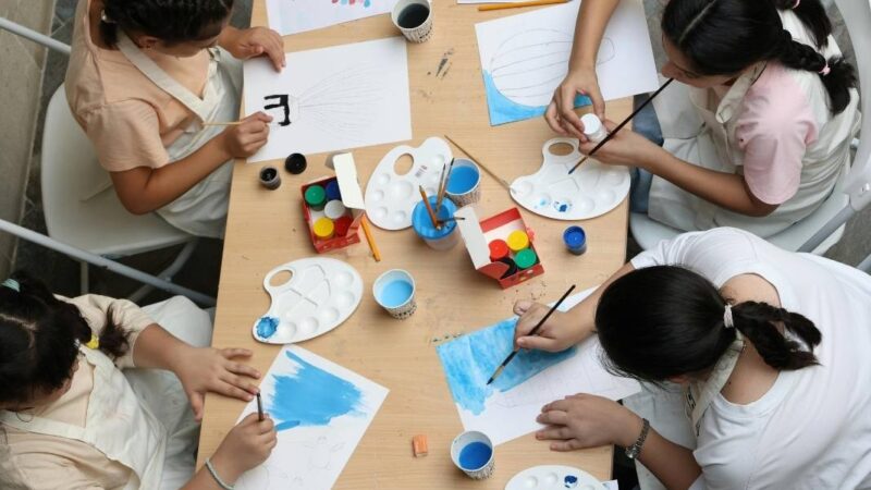 Cuatro mujeres sentadas alrededor de una mesa con materiales para pintar
