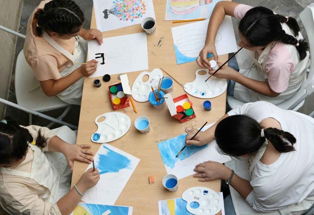 Cuatro mujeres sentadas alrededor de una mesa con materiales para pintar