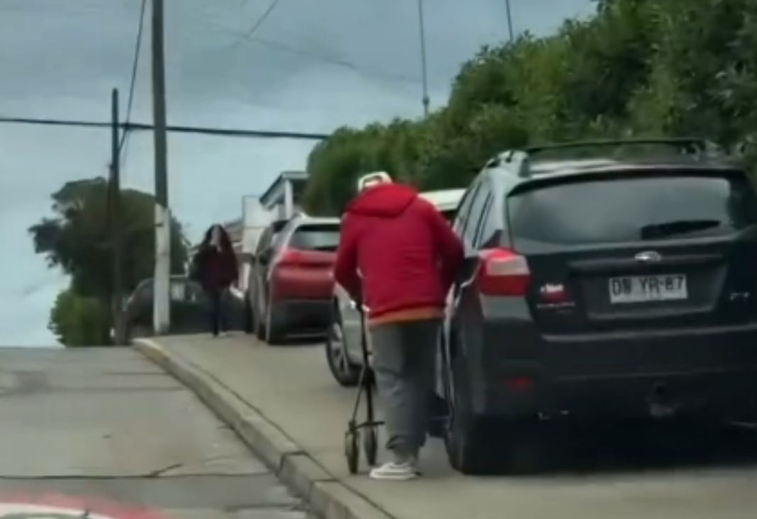 persona mayor de espalda junto a un vehículo