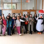 varas personas posando hacia la cámara y un corpóreo de un pinguino