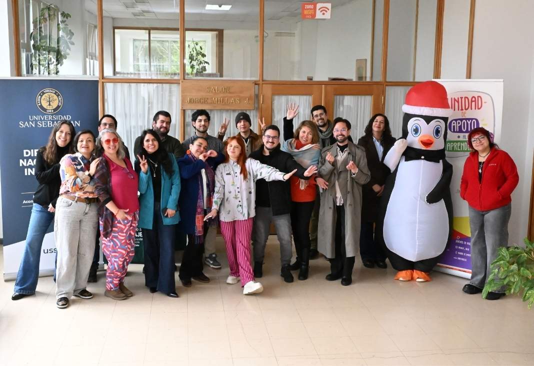 varas personas posando hacia la cámara y un corpóreo de un pinguino