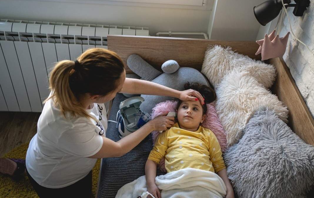 Mujer cuidando a niña enferma acostada en una cama