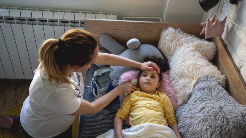 Mujer cuidando a niña enferma acostada en una cama