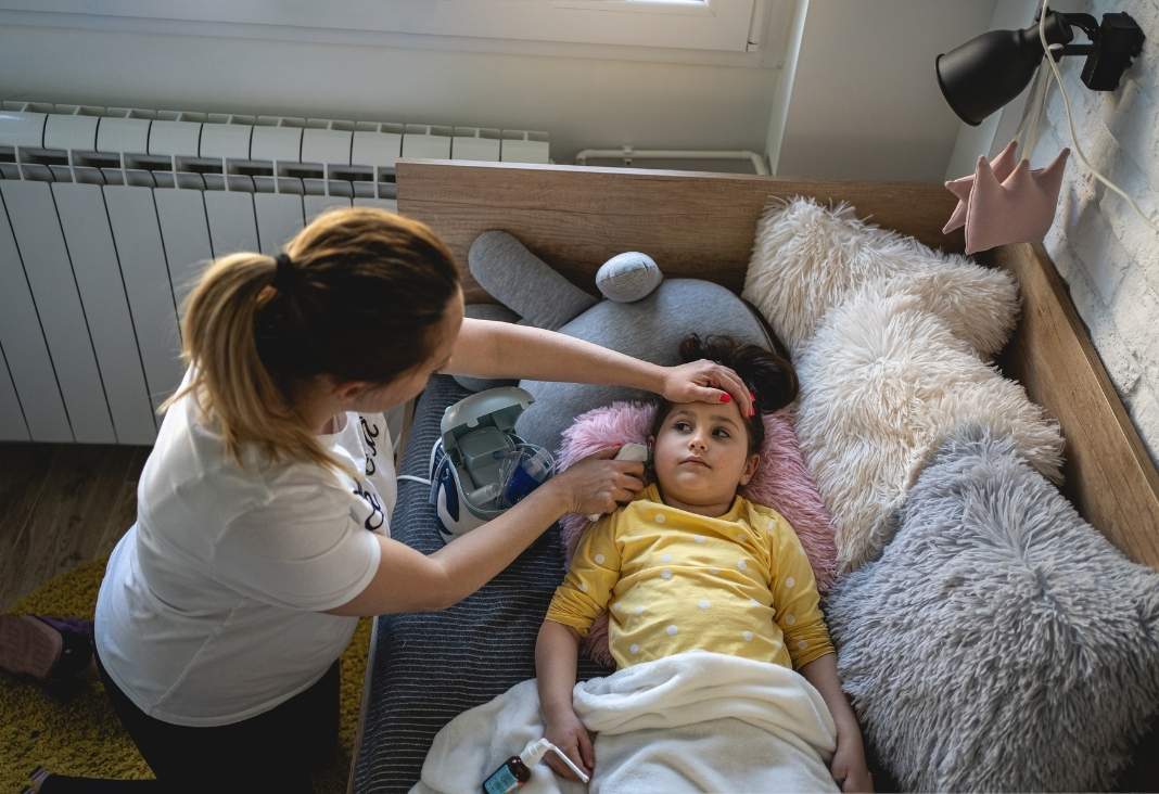 Mujer cuidando a niña enferma acostada en una cama