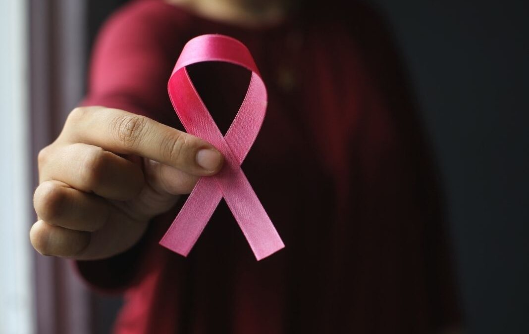 mano d emujer mostrando listón rosado por cáncer de mama
