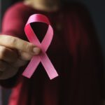 mano d emujer mostrando listón rosado por cáncer de mama