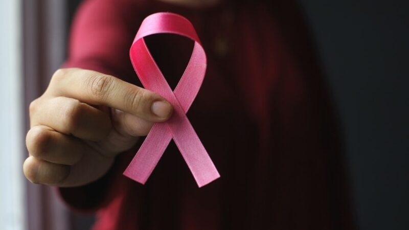 mano d emujer mostrando listón rosado por cáncer de mama