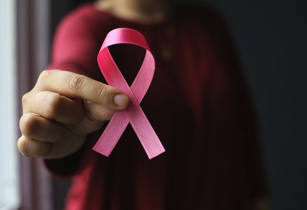 mano d emujer mostrando listón rosado por cáncer de mama
