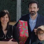 Una mujer junto a un niño con anteojos y un hombre sujetando un regalo