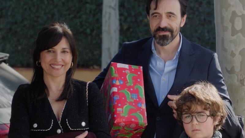 Una mujer junto a un niño con anteojos y un hombre sujetando un regalo