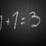 pizarra negra con letras blancas que dice 1+1=3