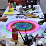 Varios materiales para pintar y una pintura de círculo con varios colores
