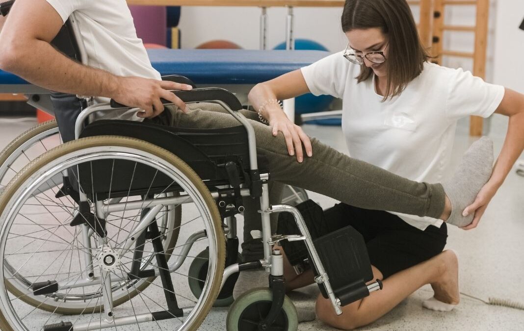 Mujer haciendo rehabilitación a persona en silla de ruedas