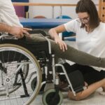 Mujer haciendo rehabilitación a persona en silla de ruedas