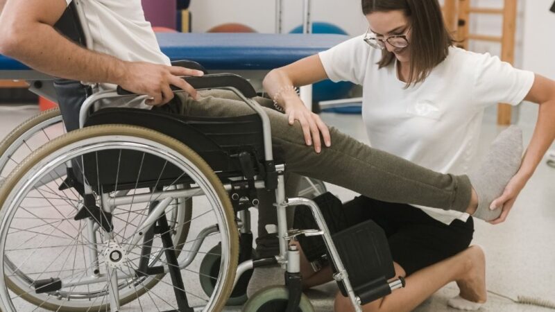 Mujer haciendo rehabilitación a persona en silla de ruedas